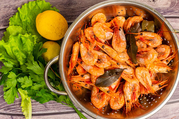 Cooked Atlantic prawns flow around in a stainless steel colander