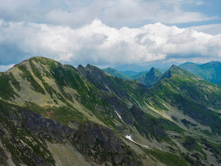 Fototapeta premium View from Banikov peak on Western Tatra mountains or Rohace panorama. Sharp green mountains - ostry rohac, placlive and volovec with hiking trail on ridge. Summer blue sky white clouds.