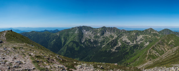 Naklejka na ściany i meble Panoramic view from Baranec peak on Western Tatra mountains or Rohace panorama. Sharp green mountains - ostry rohac, placlive and volovec with hiking trail on ridge. Summer blue sky white clouds.