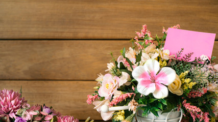 flower and blank pink note paper on it. with wood background