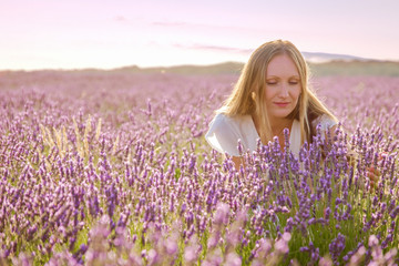 portrait of a beautiful woman smiling into purple lavender fields during a summer sunset - Image