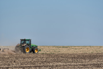 Fototapeta na wymiar Tractor plowing the ground against the blue sky