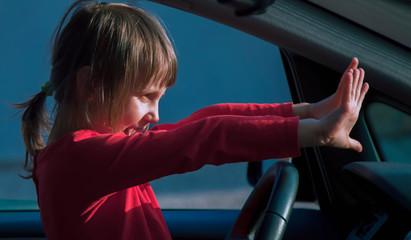 Dangers and risks of underage driving. A little child girl  panic in the car. Emergency, accident, hazard concept.