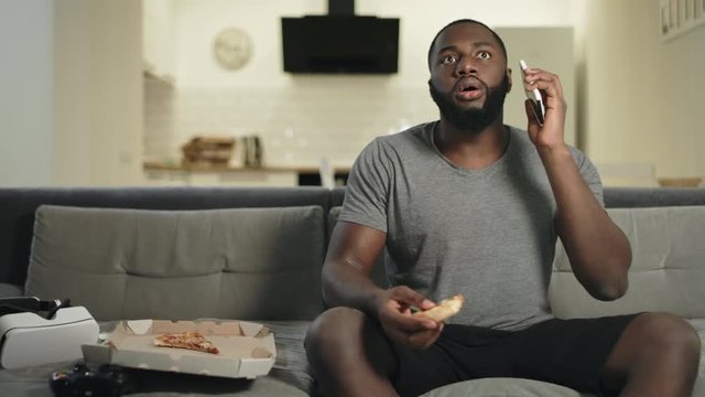 Surprised guy watching tv in open kitchen. Shocked man stopping with surprise