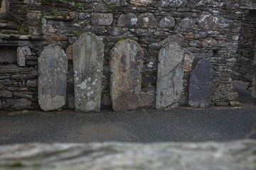 Big tombstones leaning against a stone wall