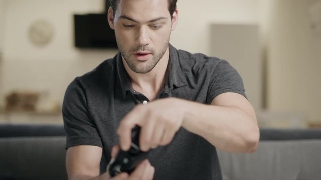 Young man playing video game. Concentrated guy taking joystick at open kitchen.