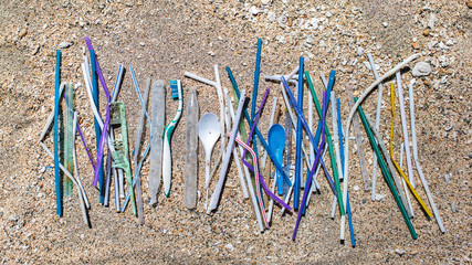 Heap of different plastic waste: straws and single-use spoons, toothbrush and comb collected on the...