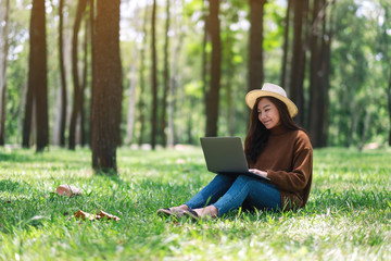 A beautiful asian woman working and typing on laptop keyboard while sitting in the park