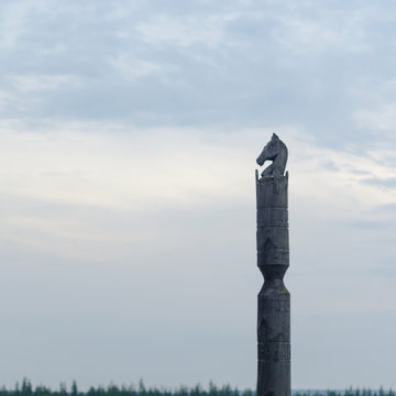 Yakut pole with horse Serge stands with the head of a horse made of wood on the background of endless tundra and forest under the clouds.