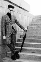 fashionable young man in glasses with umbrella standing on the stairs