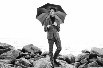  fashionable young man with umbrella standing near the sea