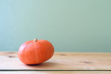Pumpkin on wooden table over neo mint background. Autumn, Halloween concept.Copy space for text.