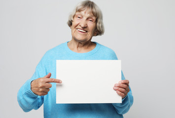 Aged woman with blank advertising board or copy spacet.