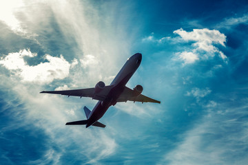 Passenger airplane in the cloudy bright blue sky. Sense of freedom.