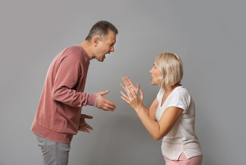 Quarrelling middle-aged couple on grey background