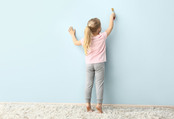 Little girl painting on color wall