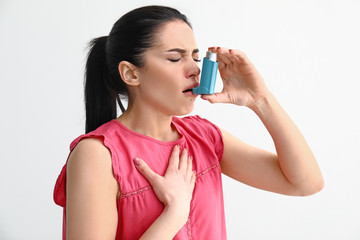 Young woman having asthma attack on light background - obrazy, fototapety, plakaty