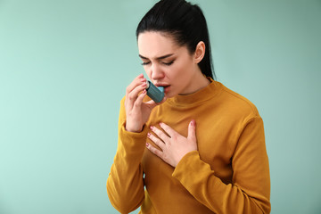 Young woman having asthma attack on color background - obrazy, fototapety, plakaty