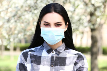 Young woman wearing protective mask on spring day