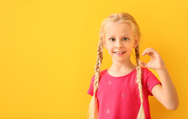 Little deaf mute girl using sign language on color background