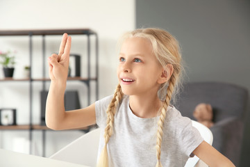 Little deaf mute girl using sign language at home