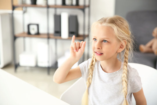 Little deaf mute girl using sign language at home