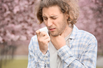 Sick man with nose wiper on spring day