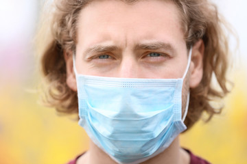 Young man wearing protective mask on spring day
