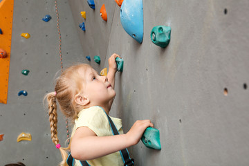 Fototapeta premium Little girl climbing wall in gym