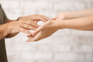 Hands of young and elderly woman on blurred background