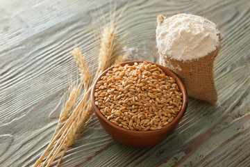 Wheat grains with flour and spikelets on wooden background