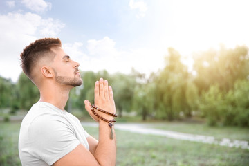 Young man praying to God outdoors