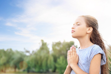 Little girl praying to God outdoors