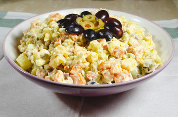Russian salad dish typical Christmas dish, decorated with grapes cut in and green olives