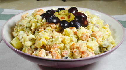 Russian salad dish typical Christmas dish, decorated with grapes cut in and green olives