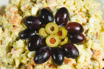 Russian salad dish typical Christmas dish, decorated with grapes cut in and green olives