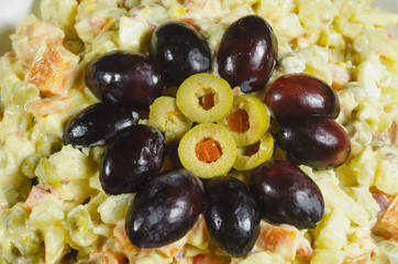 Russian salad dish typical Christmas dish, decorated with grapes cut in and green olives