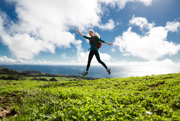 Portrait of fit positive girl jumping in the air on cloudy background with ocean view. Life people...