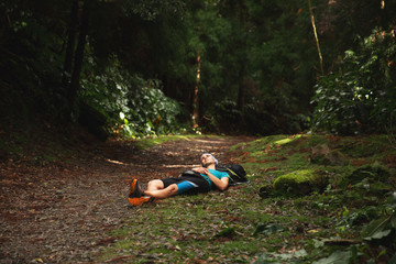 Restful young man lying down on ground in forest. Sao Miguel island, Azores