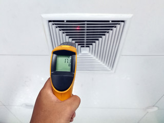Technicians are using an infrared thermometer to check the temperature of the air supply surface.