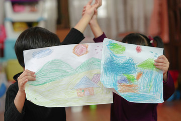 Children showing the picture or portfolio which is drawing and putting color by themselves. Education and little artist concept.    