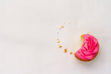 Pink bitten cupcake on a plate isolated on white background. Delicious cake. Top view.