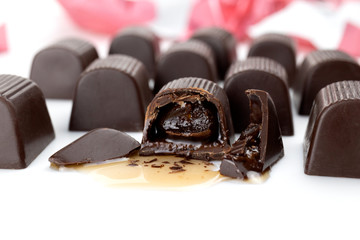 Chocolates candy on white background. Cherry with liqueur chocolate-covered in the cut. Candy, dark chocolate with a whole cherry and liqueur inside.