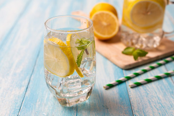Fresh lemonade with lemon in glass on wooden background