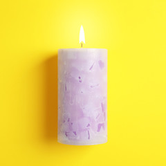 Alight scented wax candle on color background