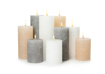 Many alight wax candles on white background