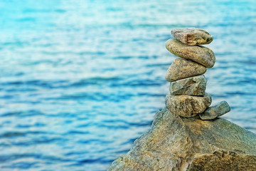 Fototapeta na wymiar Pyramid of pebbles and sea on blurred beach background. Stone Balance concept. stacked stones symbolizing stability, zen, relaxation, harmony, calm. shallow depth, soft selective focus