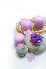 Beautiful composition with candles, flowers hydrangea, amethyst geode crystal, spa stones on blurred white background. Spa therapy composition.   Ritual for relaxation, meditation.  selective focus