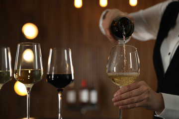 Waitress pouring wine into glass in restaurant, closeup