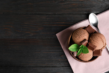 Wooden bowl of chocolate ice cream served on dark table, flat lay with space for text